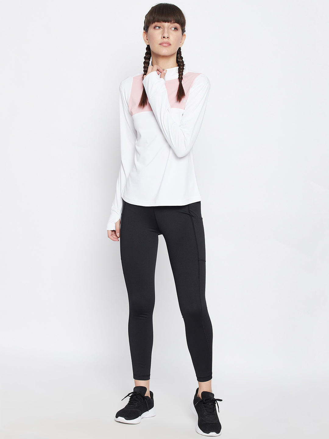 Woman in white turtleneck sweater and black leggings standing on